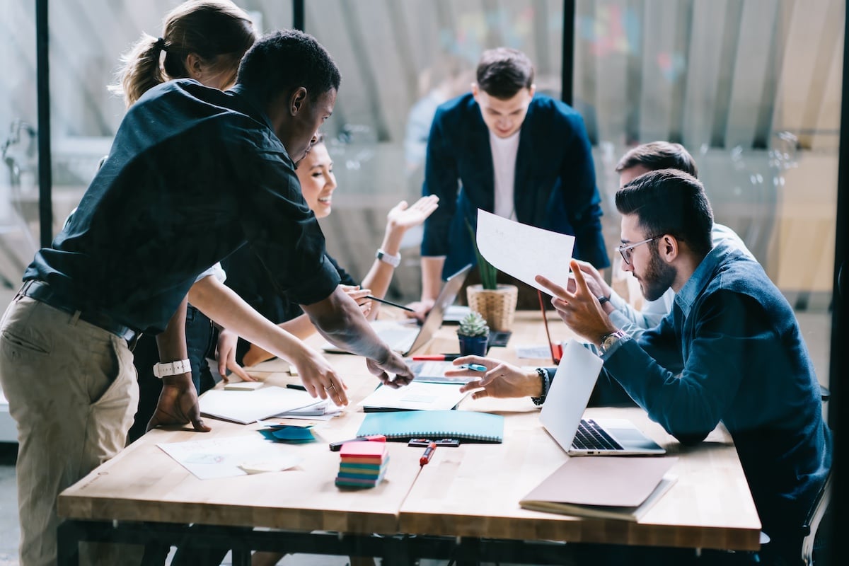 a team discussing digital collaboration in the workplace while sitting around a conference room table
